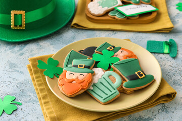 Plate with tasty gingerbread cookies for St. Patrick's Day celebration on color background, closeup