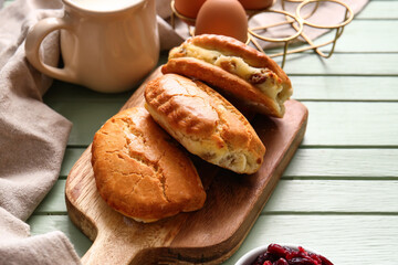 Board of tasty sochniki with cottage cheese on green wooden background