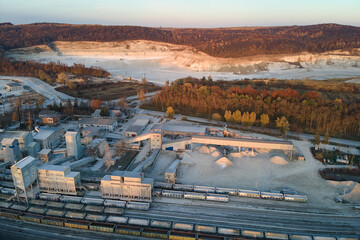 Fototapeta premium Aerial view of cargo train loaded with crushed stone materials at mining factory. Railway transportation of grinded limestone ore