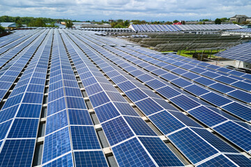 Aerial view of solar power plant with blue photovoltaic panels mounted on industrial building roof...