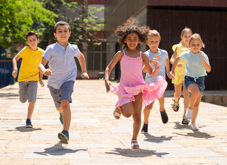 Obraz premium Group of joyful children running down the summer city street