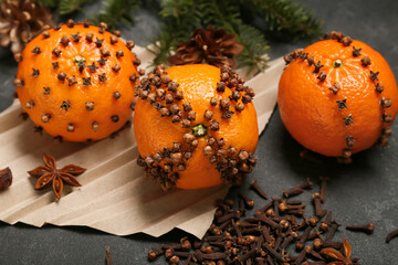 Handmade Christmas decoration made of tangerines with cloves on dark background, closeup