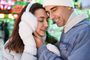 Loving couple in amusement park at winter night, closeup