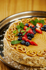 caramel cake with strawberries, blueberries and small pretzels