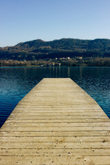 Mountain winter landscape. Small jetty in the lake with the background of the hills. Lakes of Revine Lago, Italy. Vertical image.