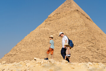 Father and children walk in front of the Chephren pyramid on the Giza plateau - Powered by Adobe