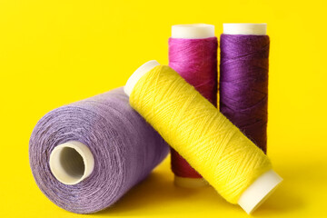 Multicolored sewing thread spools on color background