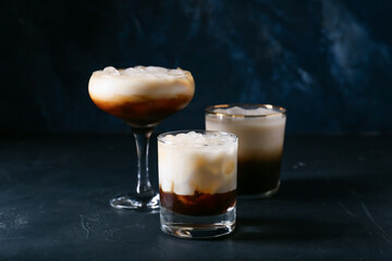 Glasses of White Russian cocktail on dark background