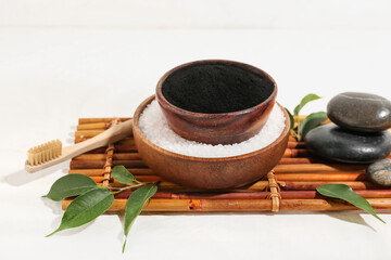 Bowls with activated charcoal tooth powder and sea salt on white background