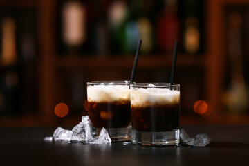 Glasses of tasty White Russian cocktail on table in bar