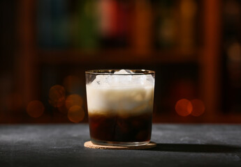 Glass of tasty White Russian cocktail on table in bar