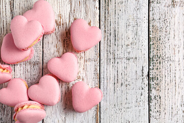 Tasty heart-shaped macaroons on white wooden background