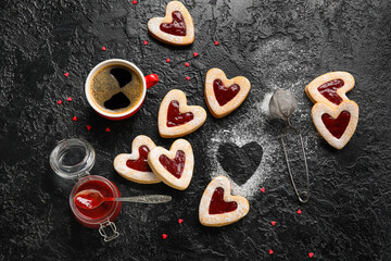 Tasty cookies and cup of coffee for Valentine's Day celebration on dark background