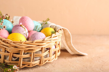 Basket with beautiful Easter eggs and flowers on color background, closeup