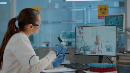Scientist talking to expert on video call conference in laboratory, using telecommunication on...