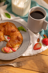Taste and with strawberries, almonds and a nutritious breakfast for one person - a ruddy croissant spread with butter, with strawberries and almonds and a cup of coffee. Culinary blog, recipe book.