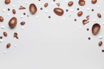 Composition with broken chocolate Easter eggs and candies on light background