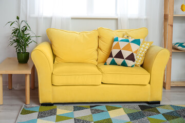 Fototapeta premium Comfortable sofa and table with houseplant in stylish living room interior
