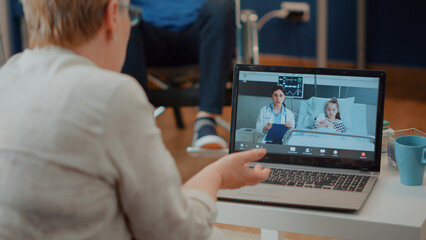 Fototapeta premium Senior woman meeting with specialist and child on videocall communication. Retired adult talking to doctor and little girl in hospital on online teleconference using laptop computer.