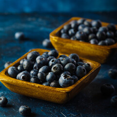 Blueberries in bowls and in bulk on the table. Dark blue background. Close-up. Vitamins, antioxidants, healthy food, ingredient for dishes, juices, fresh juices, medicine, supermarket.