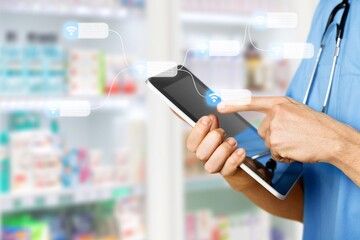 Pharmacist holding computer tablet for filling prescription in pharmacy drugstore.