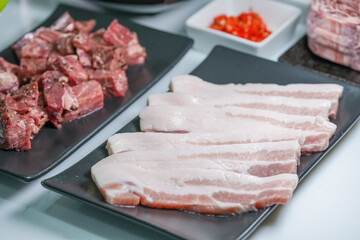 Fototapeta premium Korean beef barbecue a popular Korean dish with small side dishes set, Beef, pork, garlic, minced peppers, fresh vegetables and fresh vegetable salad for korean barbecue