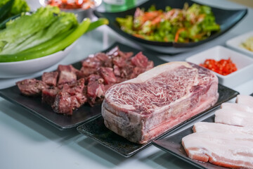 Korean beef barbecue a popular Korean dish with small side dishes set, Beef, pork, garlic, minced peppers, fresh vegetables and fresh vegetable salad for korean barbecue