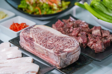 Korean beef barbecue a popular Korean dish with small side dishes set, Beef, pork, garlic, minced peppers, fresh vegetables and fresh vegetable salad for korean barbecue