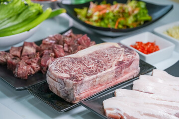 Korean beef barbecue a popular Korean dish with small side dishes set, Beef, pork, garlic, minced peppers, fresh vegetables and fresh vegetable salad for korean barbecue