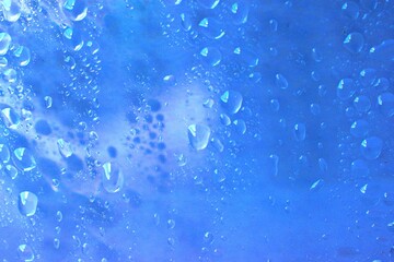 Abstract water droplets texture background on clear blue glass close-up