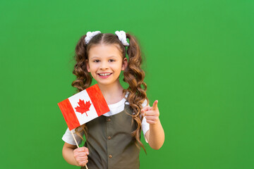 Children holds the Canadian flag and points forward. A joyful girl is studying at a Canadian...