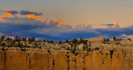 Night begins to fall on the granite Hoodoos of Bryce Canyon National Park, turning the colors of sky beautiful shades of blue and pink and the granit