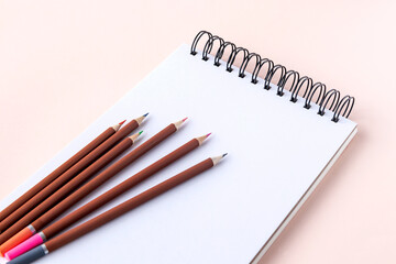 Sketchbook with white background and colored pencils for creativity.Pink isolated background. 