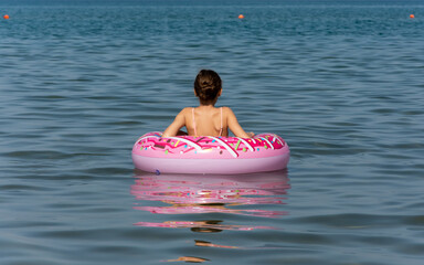 Girl sitting on inflatable ring at summer beach