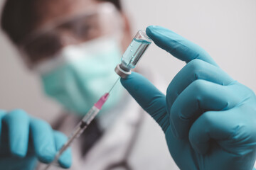 doctor or scientist in the COVID-19 medical vaccine research and development laboratory holds a syringe with a liquid vaccine to study and analyze antibody samples for the patient.
