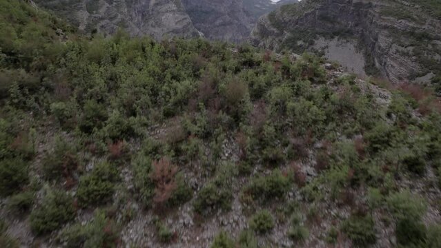 Video with Drone of plane discovery of the Sh20 highway between the mountains and the cemi river in Albania at the height of Selce, cloudy sky and winding road.