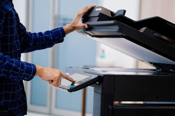 Businessmen press button on the panel for using photocopier or printer for printout and scanning document paper at office.