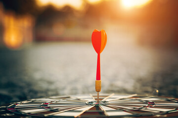 bullseye target or dart board has red dart arrow throw hitting the center of a shooting for...