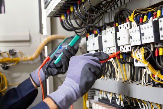 Electrician engineer tests electrical installations and wires on relay protection system. Adjustment of scheme of automation and control of electrical equipment.