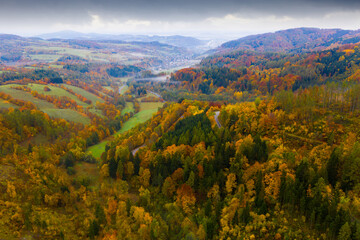 Scenic aerial view of bends of road between trees on hillsides in autumn ..