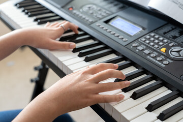 Fototapeta premium Teen hands playing an electronic piano keyboard