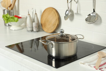Shiny pot on electric stove in kitchen. Cooking utensil