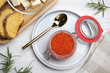 Red caviar served with bread, butter and rosemary on white wooden table, flat lay