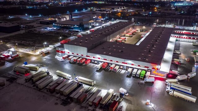 Aerial Hyper lapse (hyperlapse - motion time lapse) of a logistics park with a loading hub. Semi-trailer trucks standing at warehouse ramps for loading and unloading goods