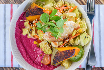 A serving of grilled chicken salad with vegetables in a round white bowl