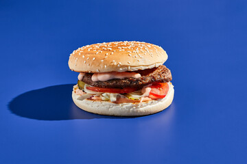 Beef burger blue background with hard shadow. American junk food minimal style. Hamburger trendy...