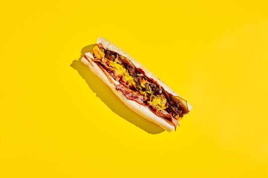 Beef cheesesteak in minimal style. American fast food in yellow background with shadow. Philly steak sandwich trendy concept. Junk food in colour background.