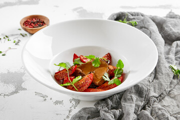 Roasted beef tongue with gravy and dried tomatoes. Meat dish from beef tongue and vegetables garnish. Delicatessen main course - ox tongue.