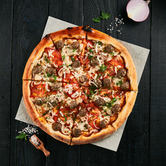 Homemade pizza with meatball on black wood background.  American pizza with meat and cheese....