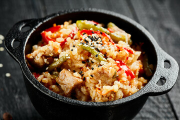 Chicken fried rice on wok. Asian food - fried rice with vegetables, egg and chicken on dark table. Wok menu on black wood background. Traditional chinese food.